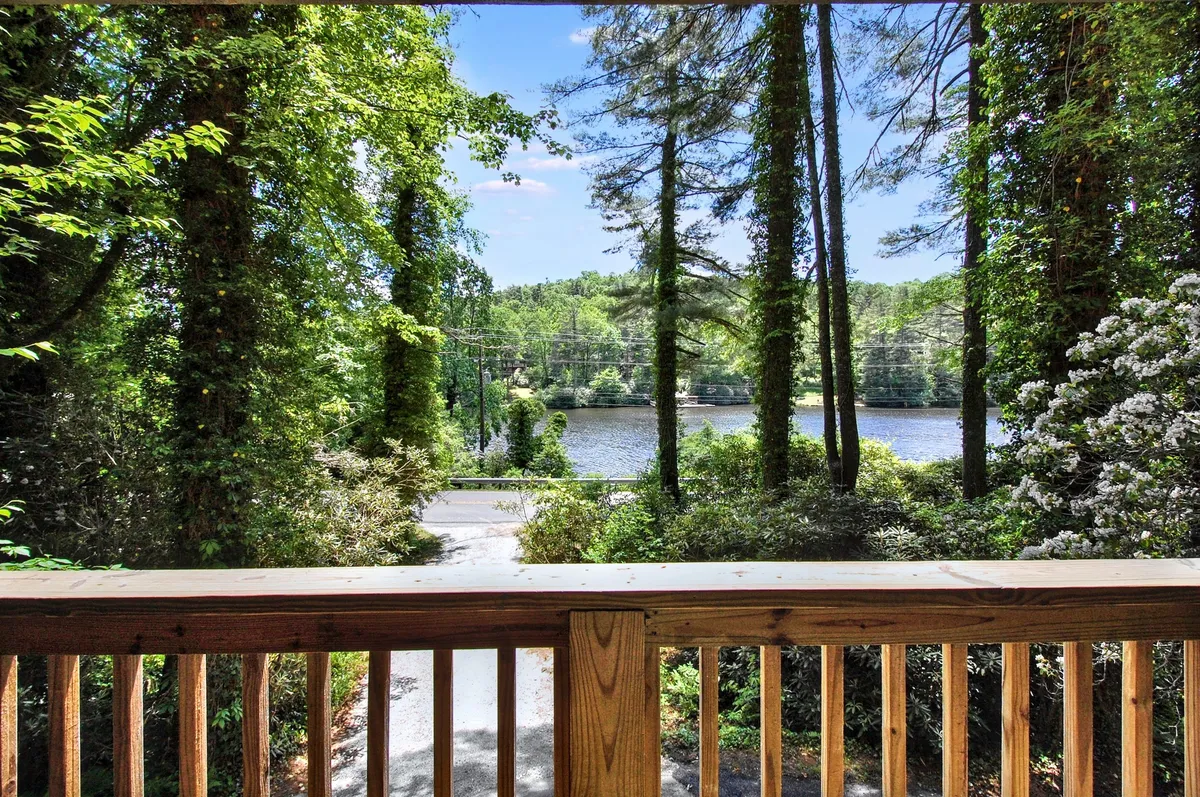 A wooden railing frames the foreground, overlooking a river embraced by thick, leafy trees. The scene exudes tranquility, perfect for nature lovers looking to unwind after a hike or take in wildlife along the water.