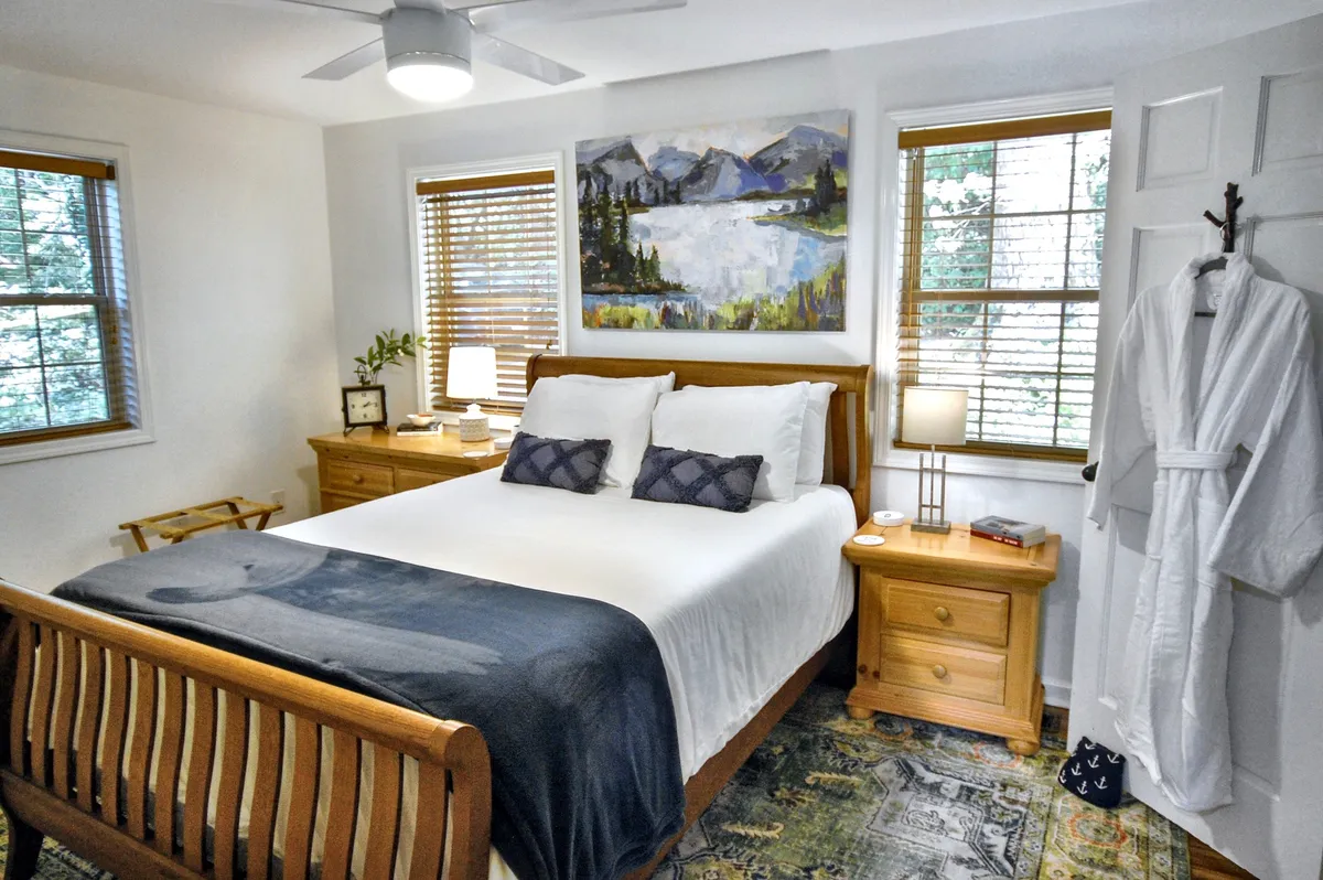 This interior shot presents a serene bedroom with a plush bed, soft natural light, and a luxurious robe draped on the bed. The cozy, inviting atmosphere suggests comfort and relaxation, perfect for couples unwinding after a day of exploration.