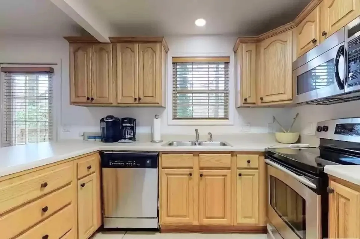 A stylish, fully equipped kitchen with modern cabinetry, stainless steel appliances, and a spacious sink, illuminated by ample natural light. The space is designed for family cooking sessions, morning breakfasts, and celebratory baking.