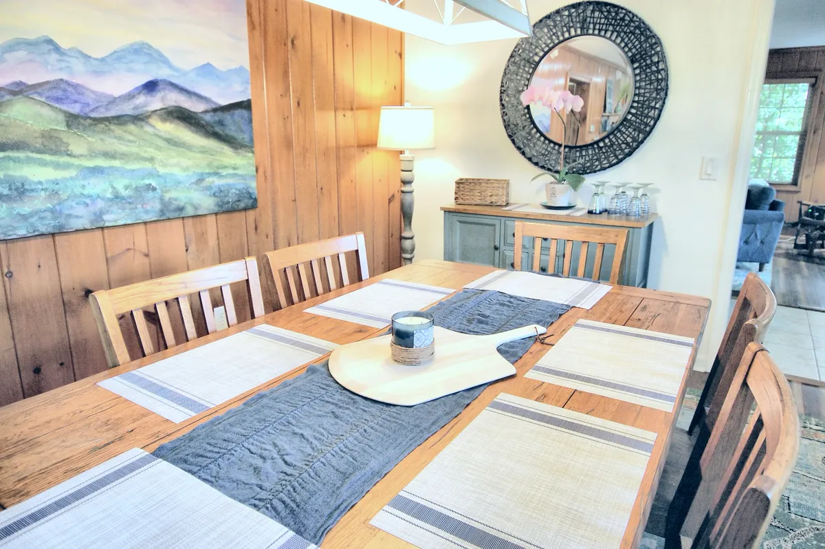 A warmly lit dining room interior with a large table, wall art, and ambient lighting, perfect for family meals or casual gatherings on rainy days. The space feels inclusive and comfortable, ideal for both play and connection.