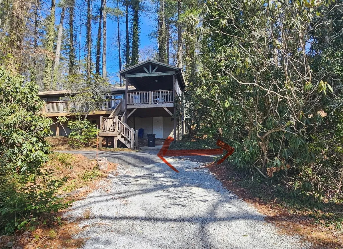 A peaceful exterior view of the house nestled among tall trees, with a clear driveway leading up to it. The house exudes a sense of seclusion and tranquility, perfect for family getaways focused on exploring nature and enjoying peaceful surroundings.